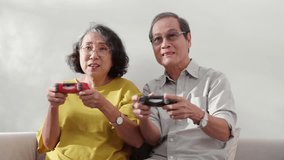 Happiness family with senior couple sitting on sofa playing game with joystick with enjoy and fun in living room at home, happy elderly man and woman relax with video game, bonding and relation.