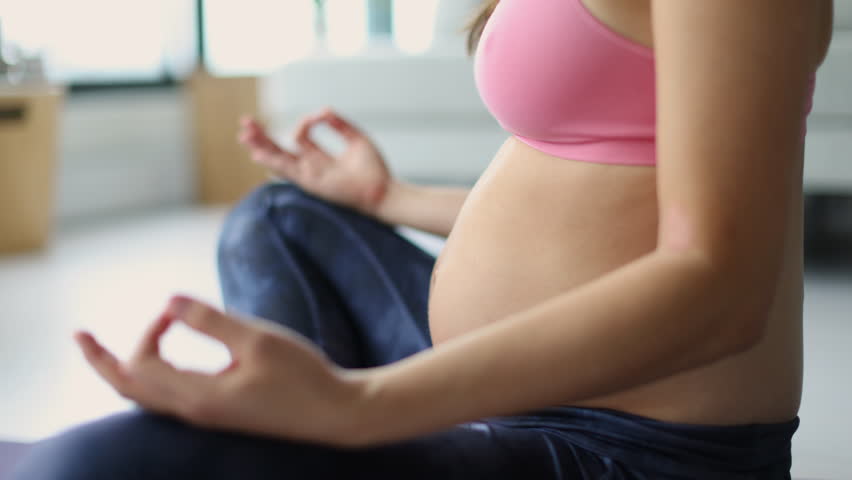 Prenatal yoga. Pregnant woman doing meditation. Woman meditating during Pregnancy at home on floor mat in lotus position practicing breathing exercises. First and Second trimester training. Royalty-Free Stock Footage #1109392395