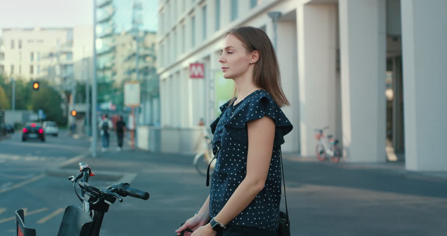 Close up of young smiling woman is putting on cycling security helmet in city center park before riding rental bicycle home after finishing her work day. Royalty-Free Stock Footage #1109398295