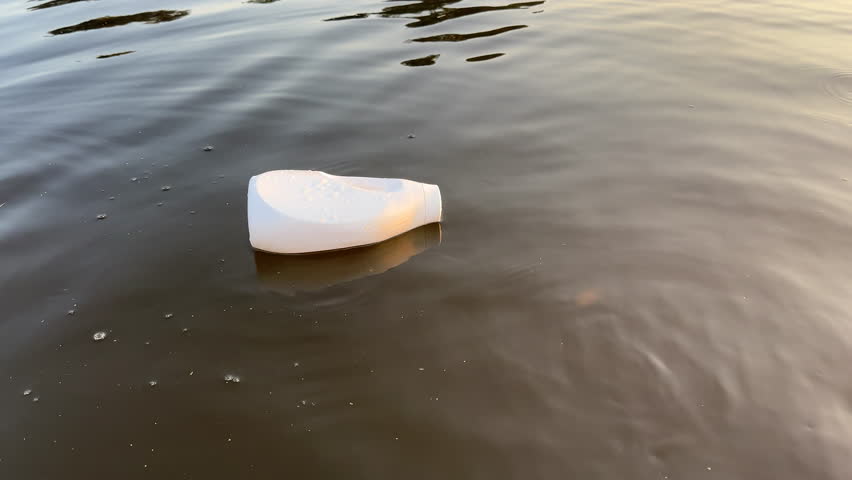 Plastic waste in lake water. Marine Plastic Pollution, Marine Debris. Wastewater Plastic bottle garbage. Litter as plastic detergent bottle from human activities at coastlines. Microplastics garbage. | Shutterstock HD Video #1109399125