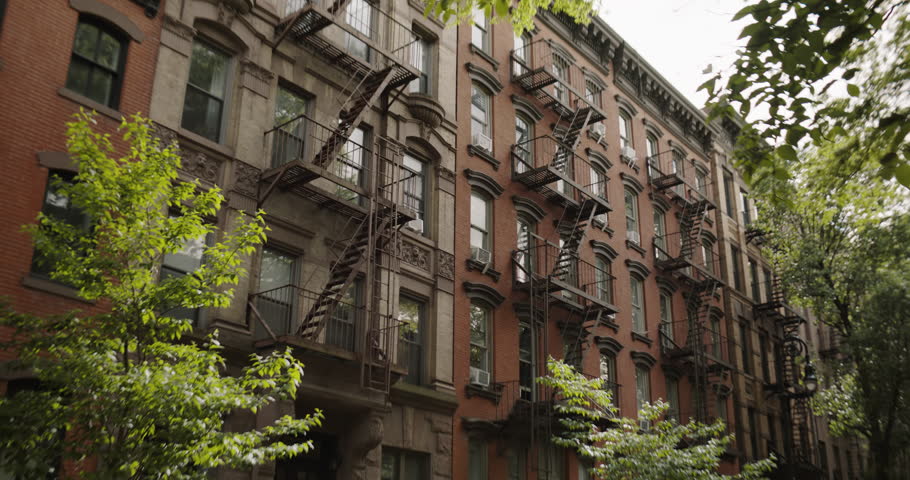 Renovated Brick Multi-Storey Apartment Building in New York City. Old Brownstone House. Urban Landscape During Day Time of a House with Emergency Stairs and Air Conditioning