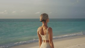 Behind attractive blond woman stretching arms upwards doing yoga on tropical beach - Powered by Shutterstock - Get 15% off with code: PIKWIZARD15