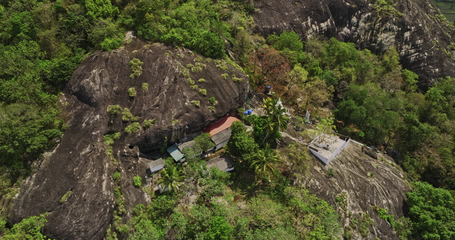 Algama Len Viharaya Sri Lanka Aerial v2 birds eye view fly around ancient hillside cave Buddhist temple, tilt up reveals jungle rock and mountain landscape views - Shot with Mavic 3 Cine - April 2023