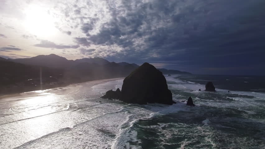 Aerial Panning Shot Of Rock Formation Amidst Waves In Sea Near Landscape Against Sky During Sunset - Portland, Oregon