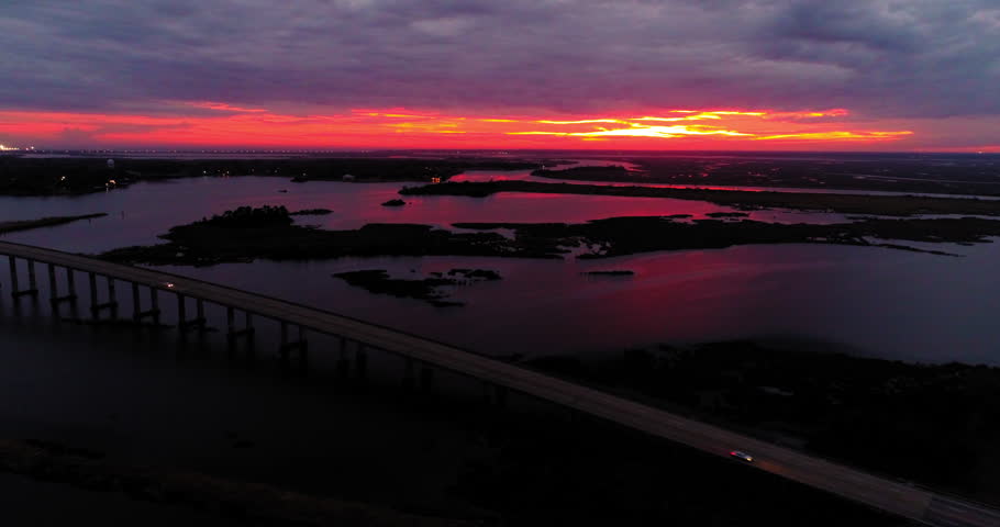 Aerial Panning Shot Of Vehicles On Bridge Over Sea Against Cloudy Sky At Dusk - New Orleans, Louisiana