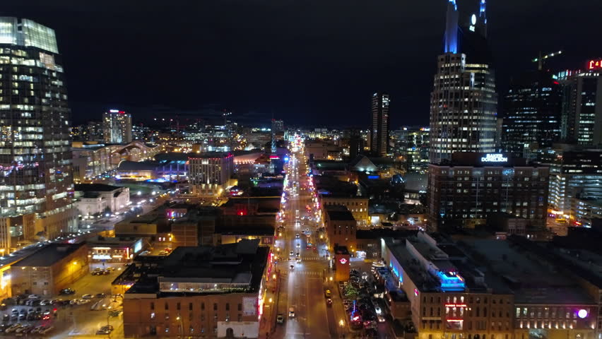 Aerial Forward Shot Of Cars Moving On Street Amidst Buildings In City Against Sky At Night - Nashville, Tennessee