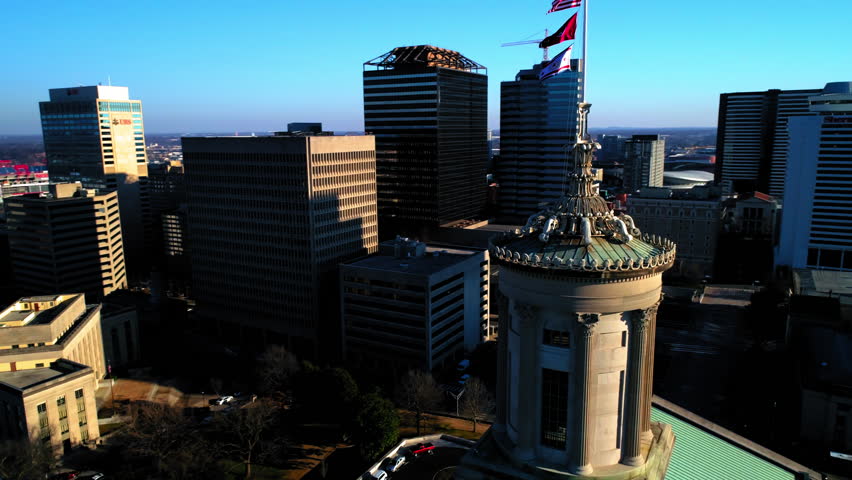 Aerial Panning Shot Of Tennessee State Capitol With Flags Near Buildings In City Against Sky - Nashville, Tennessee