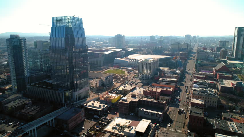 Aerial Backward Shot Of Cumberland River With Bridge Near Buildings In City Against Sky - Nashville, Tennessee