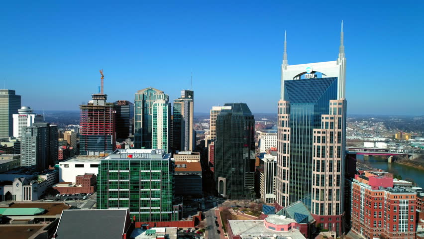Aerial Forward Shot Of Modern Buildings In City Near Cumberland River Against Blue Sky - Nashville, Tennessee