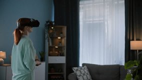 modern technology, a young woman in VR glasses calls up with friends and communicates using virtual reality video call while standing in a cozy room
