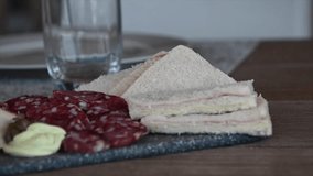 slow motion video where a woman's hand takes out a crumb and salami sandwich