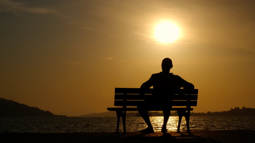 Child hug father on sea bench. A view of running daughter silohuette hugs her father on the bench by the evening bench.