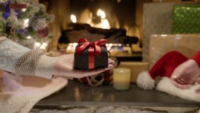 Close up hands of husband giving festive box with Christmas present to wife indoors. Beautiful decorating xmas tree, burning fireplace and celebration lights, RED camera shot holiday family party 4K - Powered by Shutterstock - Get 15% off with code: PIKWIZARD15