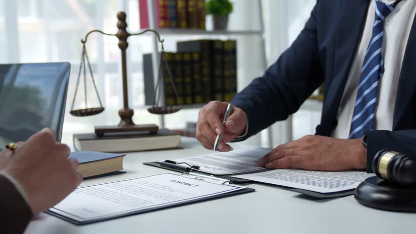 Attorneys or lawyers who are reading the statute of limitations Consultation between male lawyers and business clients, tax and legal and legal services firms. Royalty-Free Stock Footage #1109436747