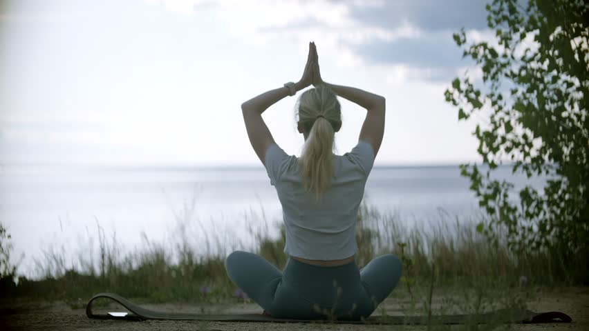 Girl Making Yoga Pose Outdoors. Beautiful Healthy Woman Breathing Gently And Sits In Pose Of Lotus. Relax Body And Mind In Nature Outdoors. Meditating And Practicing Yoga. Woman Sits On Yoga Pose Royalty-Free Stock Footage #1109440233
