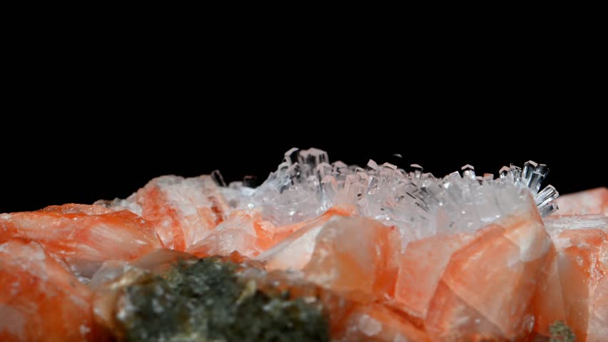 Clear Natrolite crystals on Orange Gmelinite (from Little Deer Park Quarry, Glenarm, N. Ireland) sample rotating slowly against a black background.