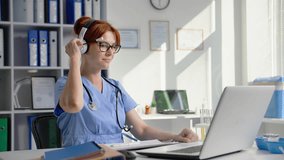 online medicine, a young female doctor communicates via video conference on laptop using a headset, tells the test results while sitting in a hospital office
