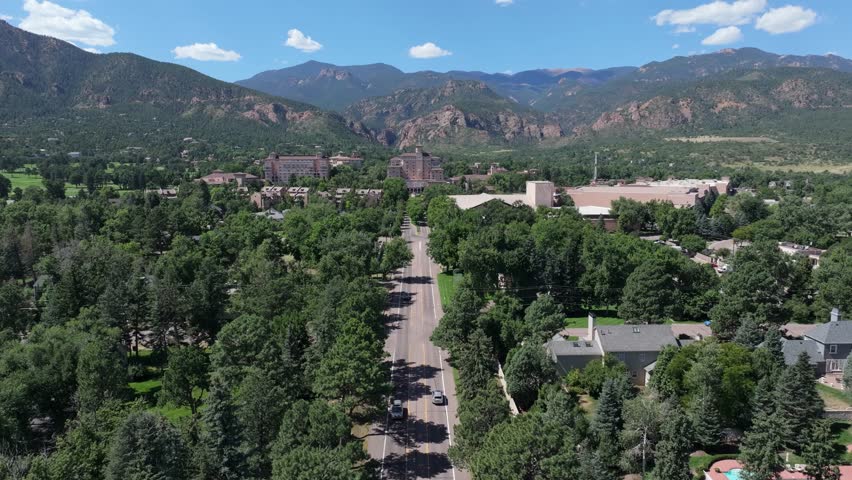 Summer day in Colorado Springs, United States. Drone landscape, traffic on road to luxury hotel building.