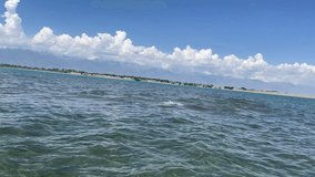 View of beautiful water surface mountains and clouds on background. Slow motion video of camera slowly submerging into deep sea at bright sunny day. Family summer holidays and trips to warm countries
