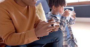 African american father and son playing video games at home, slow motion. Lifestyle, free time, childhood, communication, entertainment, family, togetherness and domestic life, unaltered.