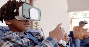 African american father and son playing video game using vr headsets at home, slow motion. Lifestyle, free time, communication, virtual reality, togetherness, family and domestic life, unaltered.