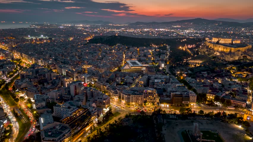 Aerial hyperlapse view of the city center of Athens, Greece, with street traffic and the illuminated, historic sites of the Acropolis in the background Royalty-Free Stock Footage #1109458915