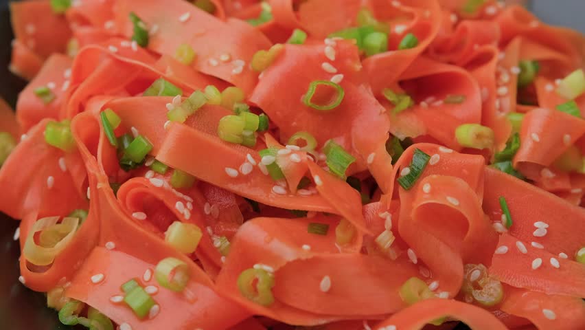 Asian carrot salad with spices and herbs in black bowl. Rotating video