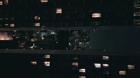 Vertical video of cinematic aerial shot fly between modern buildings at night city. Aerial view of urban architecture of metropolis with night city lights. Big City buildings at night time