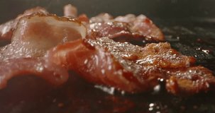 Frying halal beef bacon in pan side view macro shot slow motion. Classic breakfast spread, complete with bacon's irresistibly smoky and crispy goodness. Start the day with traditional breakfast. Fat
