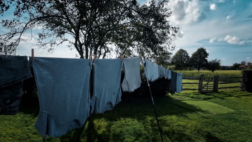 A scene of outdoor housework on a sunny day, with freshly laundered clothes hanging on the line against a backdrop of blue skies. This image captures the essence of cleanliness and freshness.
