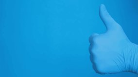 Hand in blue gloves shows thumb up isolated on blue background, Vertical video