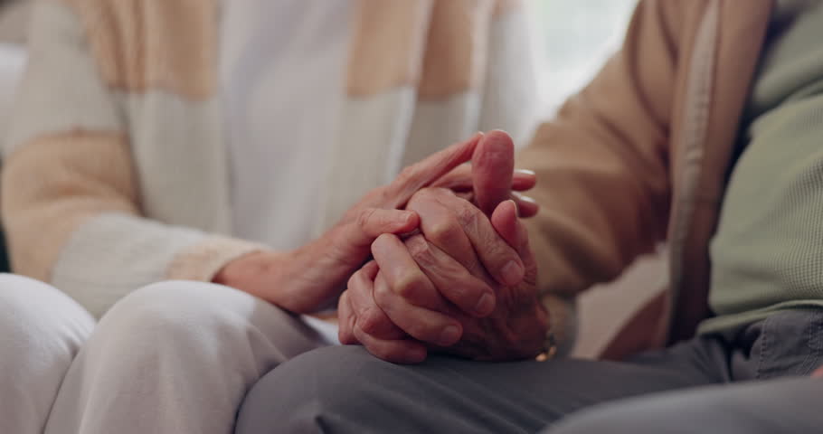 Holding hands, empathy and an elderly couple closeup in their home for love, support or trust in retirement. Hope, healing or sympathy with senior people on a sofa in the living room of their home