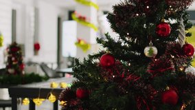 Close up shot of beautifully decorated Christmas pine tree with empty office in blurry background. Xmas tree adorn with red bows and baubles in festive workplace during winter holiday season - Powered by Shutterstock - Get 15% off with code: PIKWIZARD15