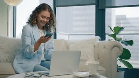 Smiling young woman using smartphone device at home. Positive millennial girl holding cell phone. Attractive blogger subscribing social media, ordering products online or buying on internet in app 4K