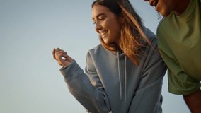 Happy youngsters kissing at blue sky background closeup. Excited woman throwing rock having fun with boyfriend at beach. Two people spending evening at summer nature together. Young lovers bonding - Powered by Shutterstock - Get 15% off with code: PIKWIZARD15