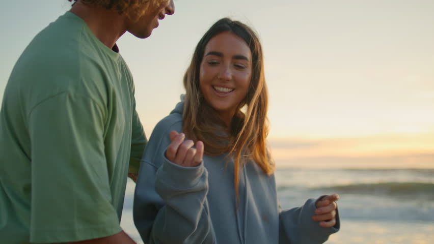 Teen couple laughing sundown ocean shore date closeup. Happy emotional youngsters communicating on evening sea beach nature background. Young romantic lovers hugging on summer trip walking together  Royalty-Free Stock Footage #1109483389
