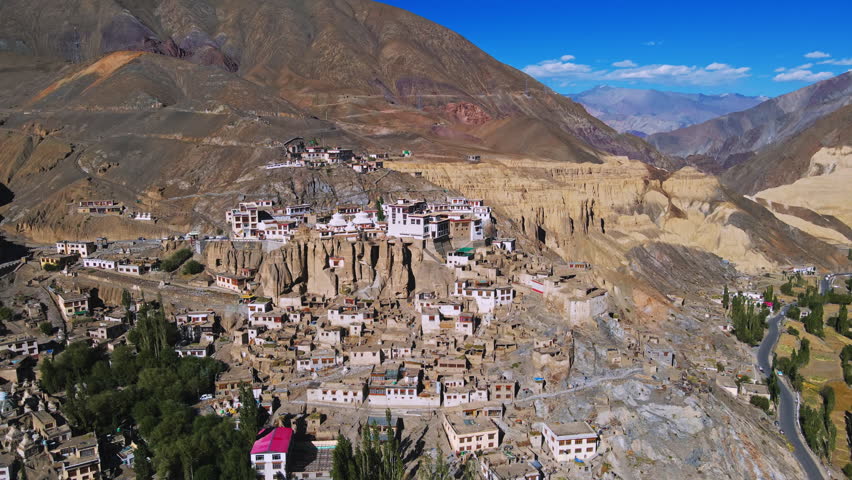 An aerial view of houses in a valley with green nature and rocky hills in Ladakh, India. Ladakh