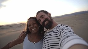 Happy multiracial young couple in love, making a selfie using phone in the desert during honeymoon for social media, looking at camera smiling and waving while showing off the landscape. - Powered by Shutterstock - Get 15% off with code: PIKWIZARD15