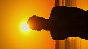 Vertical Silhouette of a young relaxed woman raises her hands up enjoying sunset, slow motion. Back view young girl looking at the setting sun. Concept lifestyle, freedom, happiness, mental wellness - Powered by Shutterstock - Get 15% off with code: PIKWIZARD15