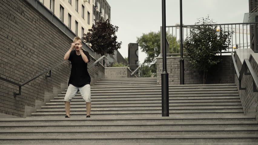 A man dances a dance with his hands. Dynamic camera, wide shot. Dancer in black clothes and shorts. - Powered by Shutterstock - Get 15% off with code: PIKWIZARD15