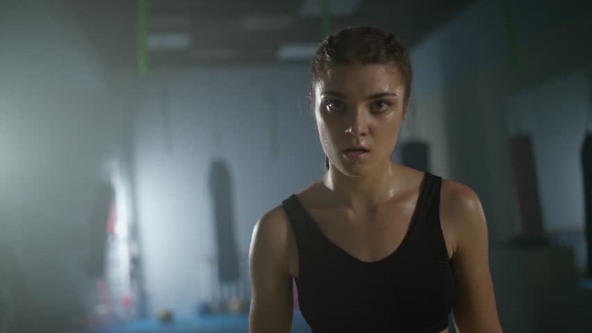 Portrait of a tired woman fighter, a screaming fighter looks into the camera after a hard fight in the boxing gym, woman power, 4k slow motion.