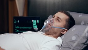 Sick man with an inhaler. An unhealthy man makes inhalations at home, uses a nebulizer and inhaler for treatment, sits on his bed at home, needs treatment.