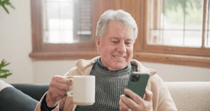 Coffee, phone and funny senior man on sofa, streaming comedy movie or video in living room at home. Drink tea, smartphone and person laugh on couch for social media meme, reading email or joke on app