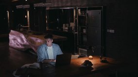 Man working late night on laptop in dimly lit loft - Powered by Shutterstock - Get 15% off with code: PIKWIZARD15
