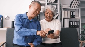 Happy mature family, wife and husband using phone together at home, smiling middle aged man and woman sitting on couch, using mobile device apps, watching video in social network, surfing internet.
