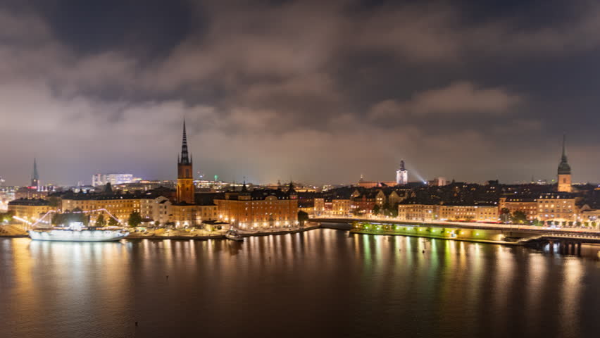 Time lapse Stockholm Sweden: city lights, night view of Stadsholmen district (Gamla Stan) and Riddarholmen district, buildings reflected in the water. Cityscape with illumination, Riddarfjarden marina