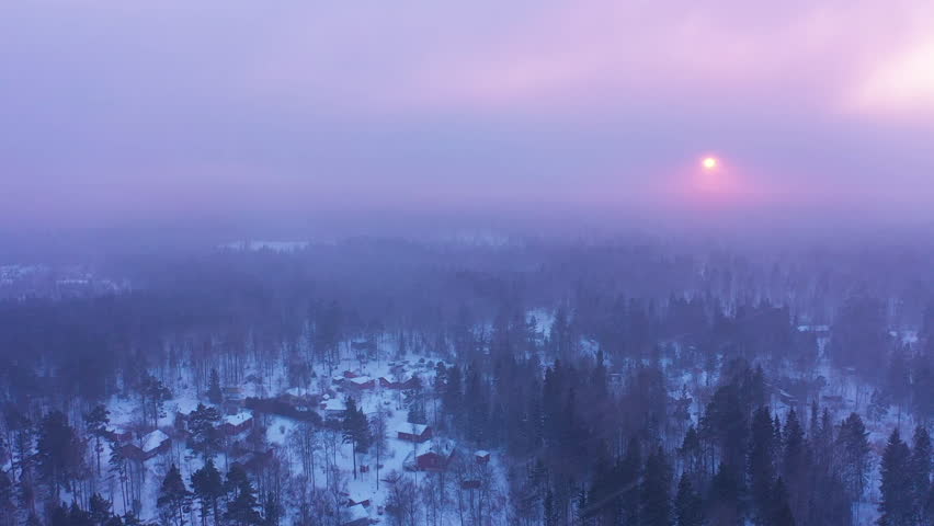 Aerial view flying over forest in sunset snowstorm winter landscape