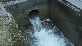 Water pouring through the dam hole. Small river dam. Natural water resources. Slow motion 4k video footage. 