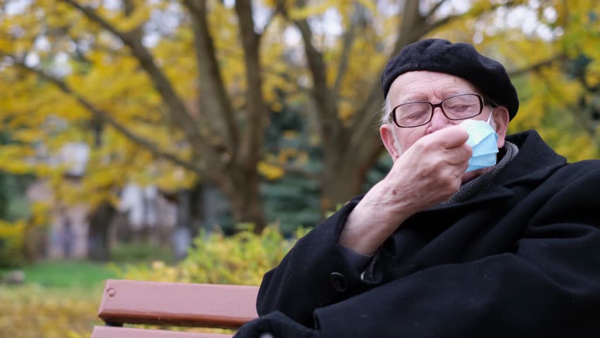 An old grandfather wears a protective mask on the street. Respiratory diseases, flu, and colds Royalty-Free Stock Footage #1109519483