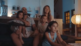 Family of Happy Woman and Man with Young Kids Watching TV and Sitting on Sofa. People Inside at Home Together Watch Television from Couch. Pretty Mixed Race Siblings Looking at News on Digital Display - Powered by Shutterstock - Get 15% off with code: PIKWIZARD15